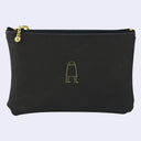 Black pouch with a gold zipper and small gold illustration on a light gray background