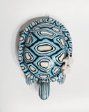 Sculpture of a blue turtle with 2 small white winged characters sitting on the turtle's shell.