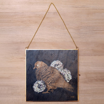 Wooden plaque with a bird and flower design hanging on a wooden wall.