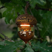 Decorative acorn-shaped sculpture, fashioned into a miniature bar with 'The Fermented Nut' text on its roof and mushroom stools in front of several beer taps.