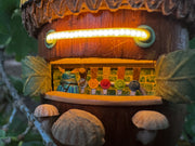 Decorative acorn-shaped sculpture, fashioned into a miniature bar with 'The Fermented Nut' text on its roof and mushroom stools in front of several beer taps.