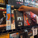 Artwork on a VHS tape of a dog looking at an old style TV, which has a very static-y screen. 