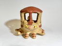 Ceramic sculpture resembling the Catbus from My Neighbor Totoro, with a house-like structure on its back against a white background