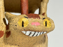 Close-up of a ceramic cat figurine with yellow eyes and brown and beige speckled body.