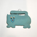 A light blue cat-shaped wall hanging or ornament with a metal loop at the top, featuring drawn facial details on a plain white background.
