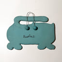 A handmade teal blue clay car-shaped wall plaque with two small round clay beads on wire hooks at the top.