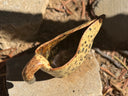 A ceramic horse-shaped pitcher with a cream and brown speckled glaze, resting outdoors on a stone surface.