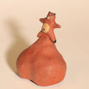 Ceramic sculpture of a tanuki - a raccoon creature - with a comically large ball sack, inflated to act as a base for him.