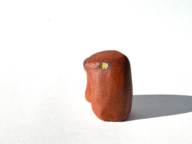 Brown ceramic sculpture of an abstract dog with a tiny face on a white background