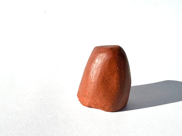 Brown ceramic sculpture of an abstract dog with a tiny face on a white background