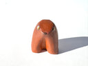 Brown ceramic sculpture of an abstract dog with a tiny face on a white background