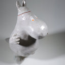 Ceramic sculpture of Moomin, posed like Frankenstein with its arms up and a line running across its head.