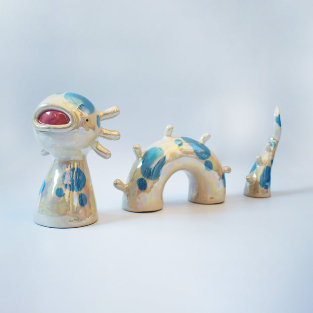 Set of ceramic sculpture, 3 pieces, making up a sea monster made to look partially submerged in water. It has a wide, open mouth, spots on its body and rounded spikes on its back.