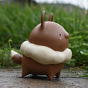 Ceramic figure of a cute, brown animal-like character with a fluffy cream colored fur collar around its neck.