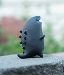 Ceramic kaiju-shaped incense burner with smoke emerging against a blurred natural background