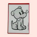 Artwork a stylized cartoon dog holding a bone, The print has a red border and is displayed against a solid pale pink background.
