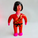 Toy figure in a red outfit with black hair on a light gray background