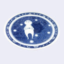 White ceramic round plate with a floral design as the border and a main circular design of a white cartoon-like character laying on a bed of flowers alongside a dark blue blob character. Side view.