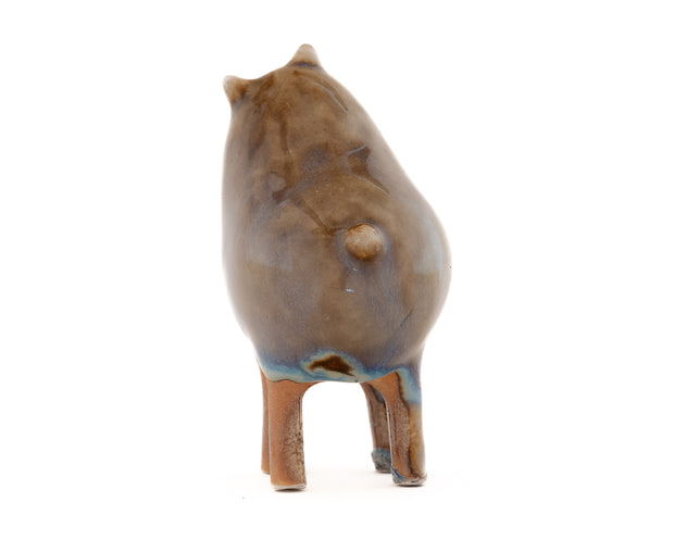 Ceramic sculpture of a brown character with a rounded body, small ears and eyes and skinny legs and no other body features.