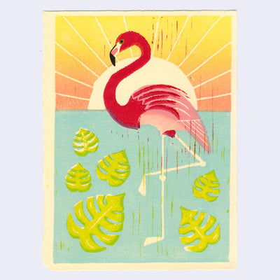 Relief print of a flamingo in a body of water with large leaves. A bright sunset shines behind it.