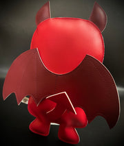 Back view of red vinyl plush, with pointed tail and wings.