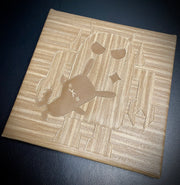 Square canvas covered in wood grain pleather fabric, with a Big Boss Robot holding a small rabbit under its arm in the center of the piece. The robot is the same wood grain pattern, though in a different direction so it is slightly more visible.
