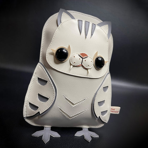 Pleather plush sculpture of a grey owl, with a simplistic silhouette. Its head is like a cat, with cat ears, stripes atop its head and a fanged muzzle.