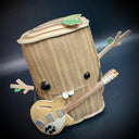 Vinyl fabric plush of a tree stump, with different sized shiny eyes and a buck tooth smile. It has its branch arms extended out in excitement and has a guitar strapped around its body.