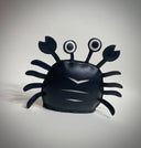 VInyl plush of a black crab with cute, google-y eyes that are also made out of vinyl.