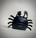 VInyl plush of a black crab with cute, google-y eyes that are also made out of vinyl.