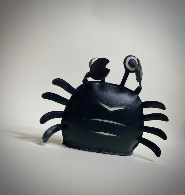 VInyl plush of a black crab with cute, google-y eyes that are also made out of vinyl.