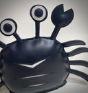 VInyl plush of a black crab with cute, google-y eyes that are also made out of vinyl.