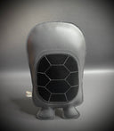 Gray flat plush of a turtle, seen from the back, with a black geometric pattern on a gray background