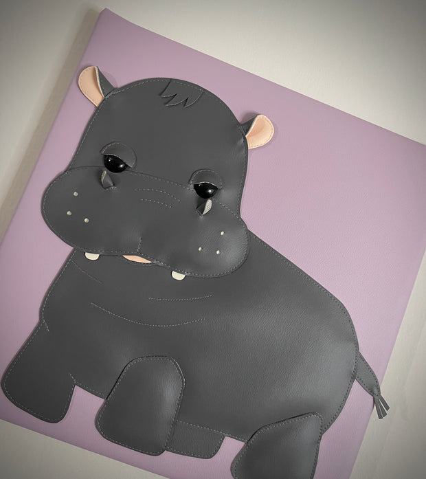  Vinyl fabric sculpture of a cartoon style baby hippo on a lilac colored square canvas.