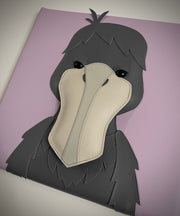 Vinyl fabric sculpture of a cartoon style shoebill bird, looking straight on so its beak looks flat on a lilac colored square canvas.
