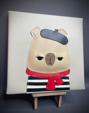 Artwork made of vinyl fabric on a flat vinyl canvas of a capybara looking unimpressed and wearing a beret, striped shirt and red scarf. 