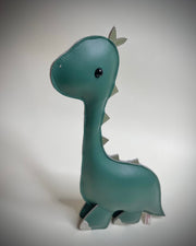 Plush, mostly flat, sculpture of a long necked green dinosaur with cute beaded eyes.
