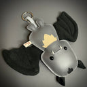 Gray plush bat keychain with black accents on a gray background