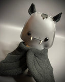 Gray plush toy with a smiling face and black eyes on a gray background