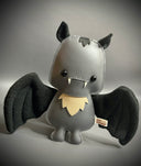 Gray plush toy with bat wings on a gray background