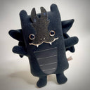 Black plush doll of a stylized dragon, with cute brown eyes and a ribbed stomach.