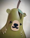 Vinyl plush flat sculpture of a pear with a bear face, small bear ears and small clawed hands.
