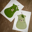 Flat vinyl fabric plush of a pear with the face of a bear and small clawed hands. 2 copies of the same design.