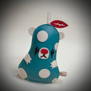 Flat vinyl fabric plush sculpture of a pear modeled like a bear, with a blue body, white accents and white polka dots. It has clown makeup with a red nose and red leaf.