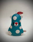 Flat vinyl fabric plush sculpture of a pear modeled like a bear, with a blue body, white accents and white polka dots. It has clown makeup with a red nose and red leaf.