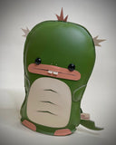 Vinyl fabric plush of a flat dinosaur/kaiju monster with a wide mouth and 2 buckteeth.
