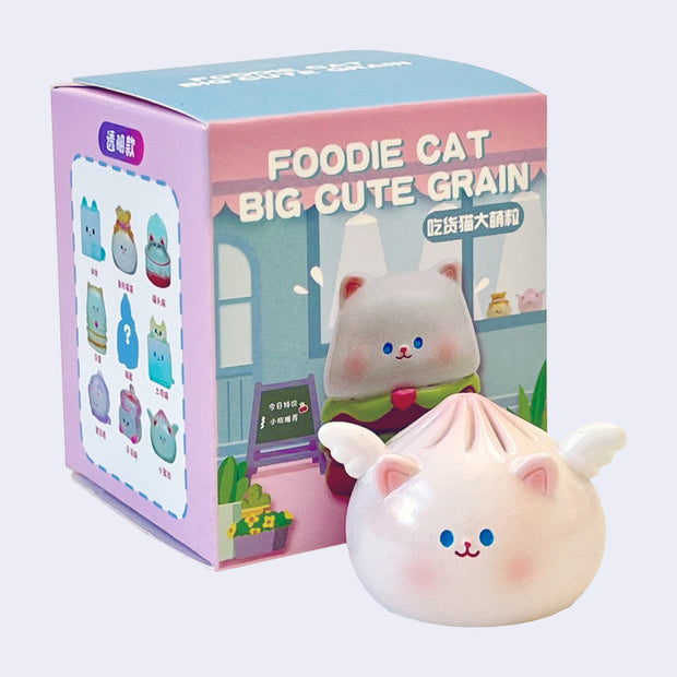 Small pink figure of a dumpling, with tiny wings and a cute, small cat face and cat ears. It sits next to its product packaging.