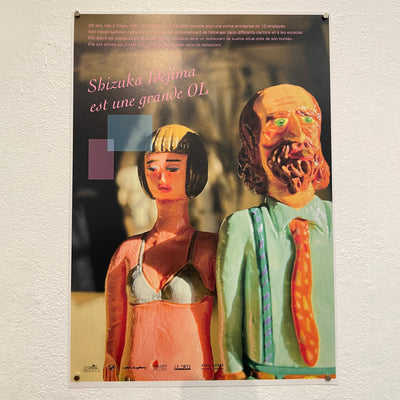 Faux movie poster for "Shizuka Idejima is a BIG OL" featuring posed vinyl figures in a scene of a sad woman and a bearded business man next to her.