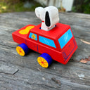 Toy car with a dog character on top, placed on a wooden surface.