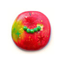 Flat backed sculpture of a red apple with small bite holes and a tiny green worm coming out of it.